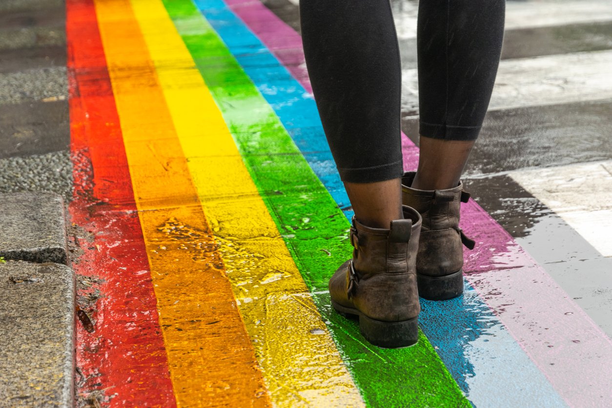 Legs walking across a LGBTQ pride flag painted on the ground